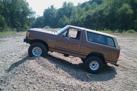 1987 Ford Bronco - Brown 1987 Ford Bronco navigating rough terrain.