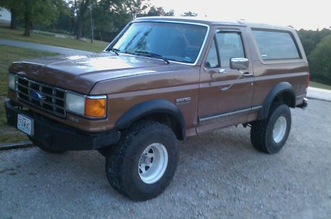 1987 Ford Bronco - This 1987 Ford Bronco is shown from a 3/4 front angle, highlighting its lifted suspension and off-road tires.