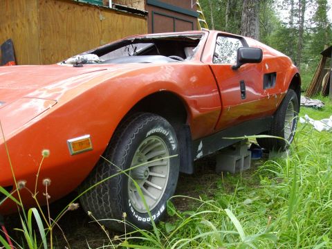 2000 Ford E350 - An orange sports car with a damaged windshield sits on cinder blocks in a grassy area.