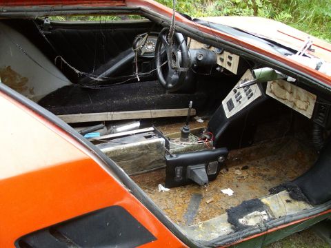 2000 Ford E350 - The interior of an orange sports car shows significant wear and tear, with exposed wiring and damaged upholstery.