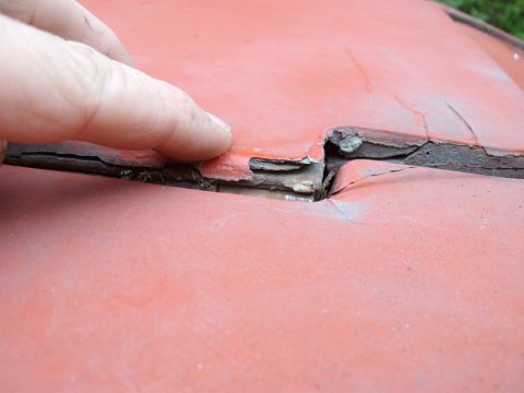 2000 Ford E350 - Close-up of damaged red painted surface with peeling paint and a visible crack.
