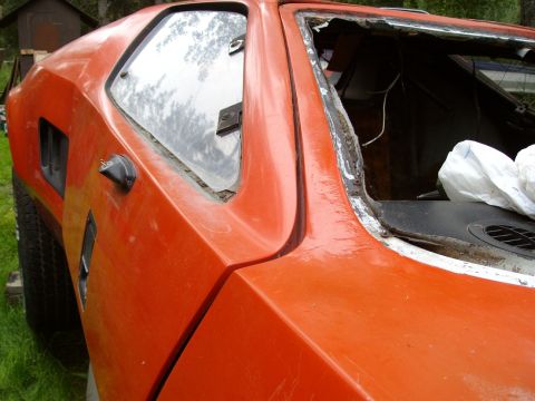 2000 Ford E350 - Close-up of an orange car's side panel and damaged rear window area.