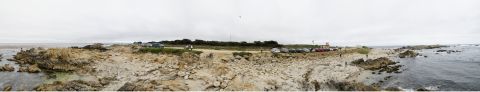 1995 Ford Taurus - A panoramic view of a coastal area with several vehicles parked near a rocky shore under an overcast sky.