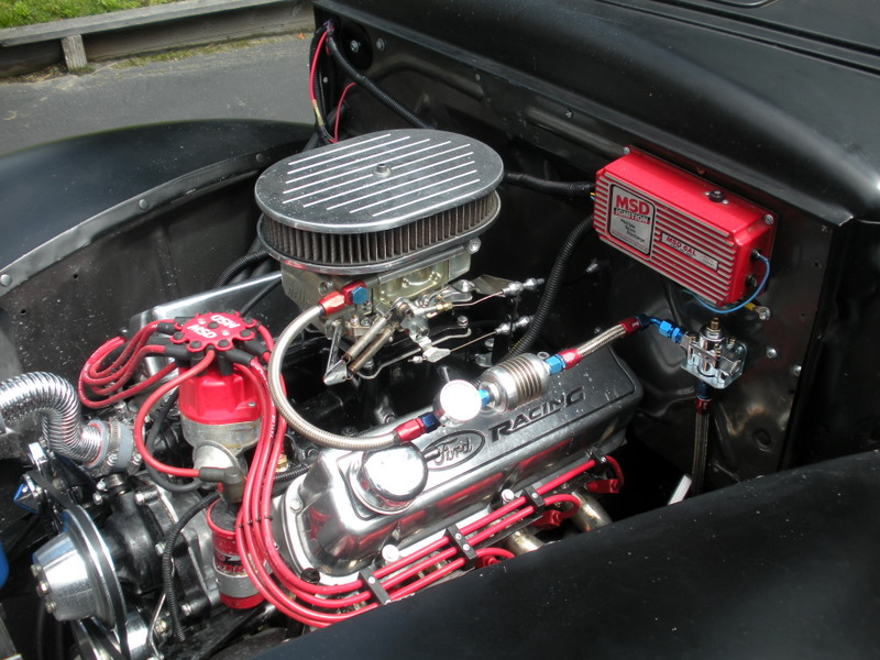 Engine bay of a 1941 Ford Pickup showing a Ford Racing engine with chrome valve covers and red spark plug wires