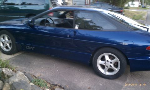 1994 Ford Probe - Side view of a blue 1994 Ford Probe GT, parked on a driveway with another vehicle behind it.