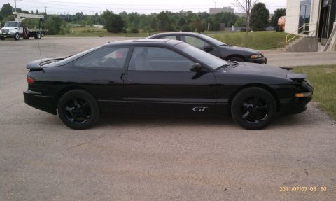 1994 Ford Probe - Side profile of a black 1994 Ford Probe GT, parked next to another vehicle.