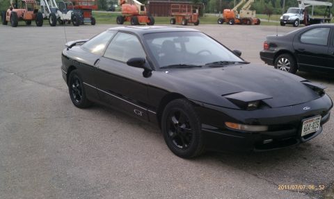 1994 Ford Probe - A black 1994 Ford Probe GT is parked in an outdoor lot with construction vehicles in the background.