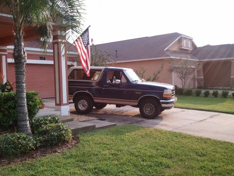 1994 Ford Bronco - A dark blue Ford Bronco is parked in the driveway of a suburban home.