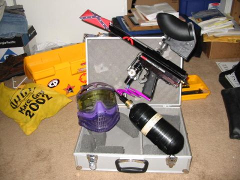 1986 Ford Bronco - A collection of paintball equipment is laid out, including a marker, mask, and air tank, alongside other items.