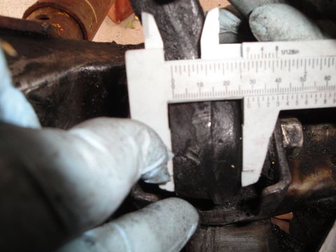 1995 Ford Taurus - Calipers are used to measure a dark metal part, likely a component from a vehicle's subframe.