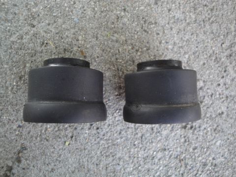 1995 Ford Taurus - Two black rubber suspension bushings are shown resting on a concrete surface.