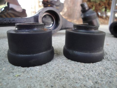 1995 Ford Taurus - Close-up of automotive suspension components, including bushings and a control arm, resting on concrete.