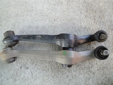 1995 Ford Taurus - Comparison of two automotive control arms, one old and one new, on a concrete background.