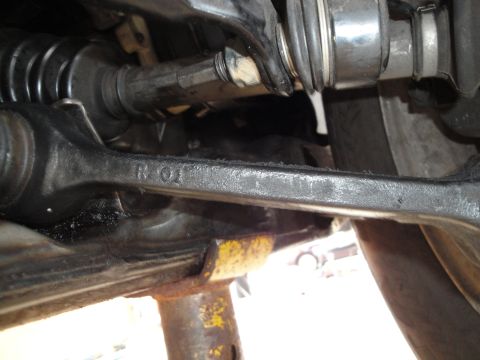 1995 Ford Taurus - Close-up of car suspension components, including a stamped part and a jack, with no visible year identification.