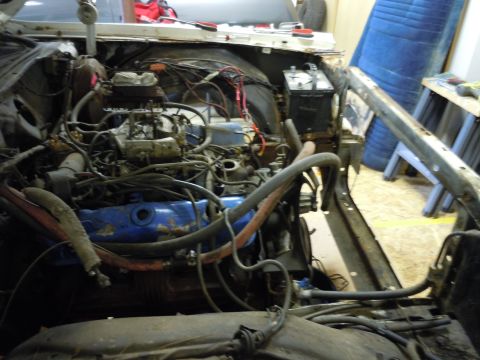 2001 Ford Crown Victoria - Close-up view of a vehicle's engine bay, blue valve covers and a carburetor, with various hoses and wiring visible.