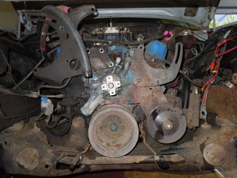 2001 Ford Crown Victoria - The engine bay of a vehicle, a V8 engine with visible hoses, brackets, and pulleys, showing signs of rust.