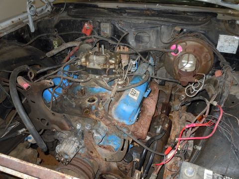 2001 Ford Crown Victoria - The engine bay shows a carburetor and blue valve covers, with visible rust and wiring.