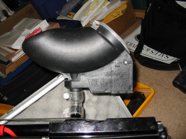 Black Viewloader paintball hopper resting on a metal case