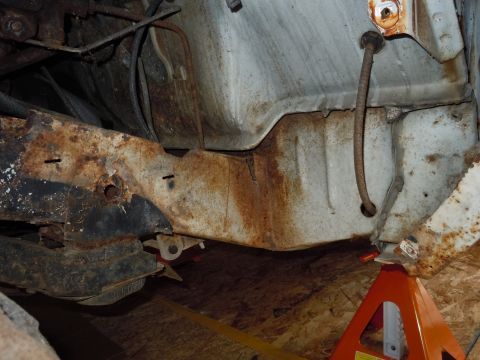 2001 Ford Crown Victoria - Undercarriage view showing significant rust on the frame and body panels, supported by orange jack stands.
