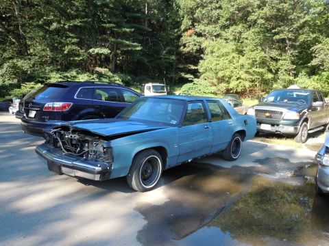 2001 Ford Crown Victoria - This blue sedan has a heavily damaged front end, with the hood open and engine components exposed.