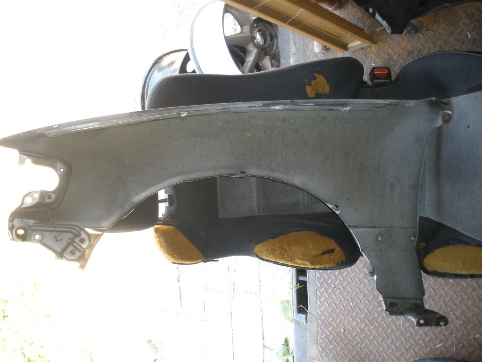 Car fender with yellow insulation visible inside wheel well. Part of a car being dismantled
