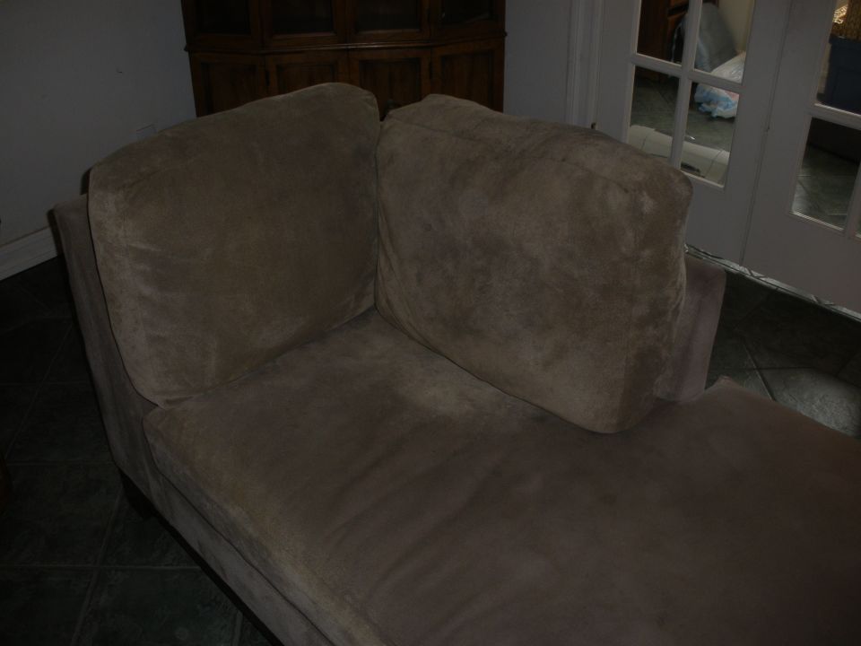 Brown chaise lounge with two large cushions, in a room with a wooden cabinet and glass doors