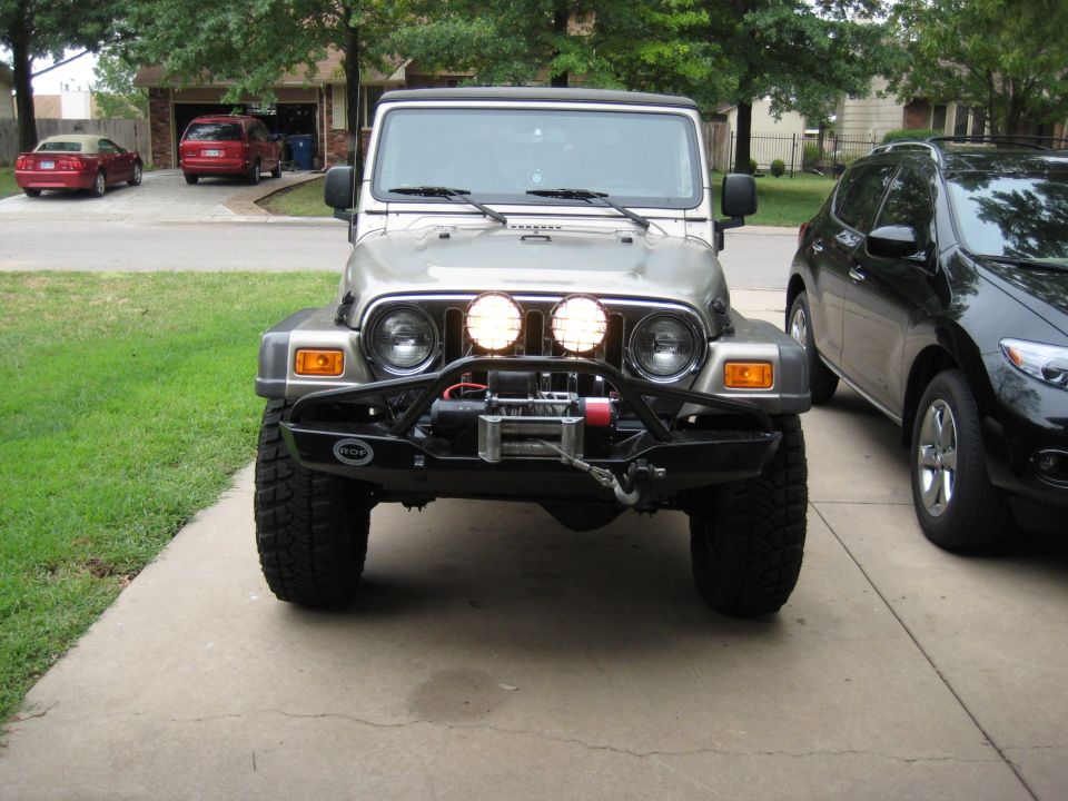 Silver Jeep Wrangler front view with aftermarket bumper, winch, and PIAA lights