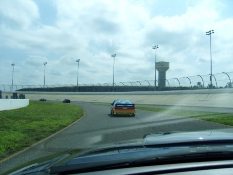2007 Ford Mustang - Cars race on a track under a cloudy sky, with a water tower visible.