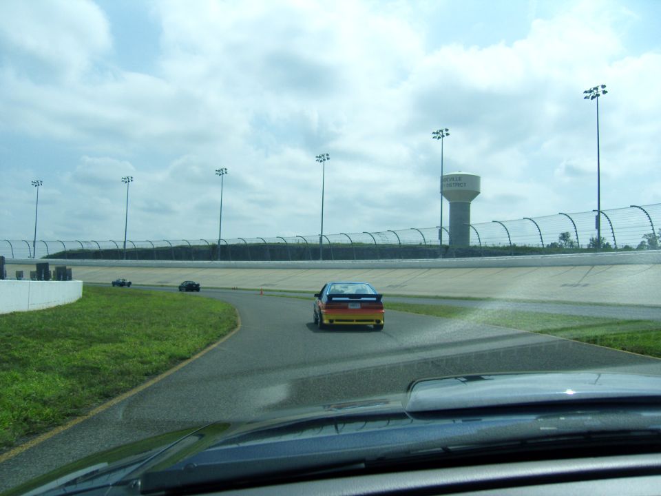 Cars on a race track with a water tower in the background