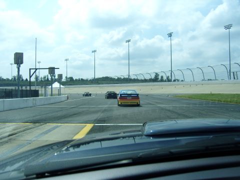 2007 Ford Mustang - Several cars are driving on a race track under a cloudy sky.