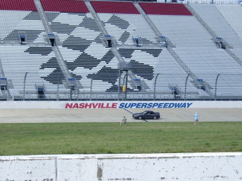 2007 Ford Mustang - A dark coupe is parked on the track in front of the Nashville Superspeedway grandstands.