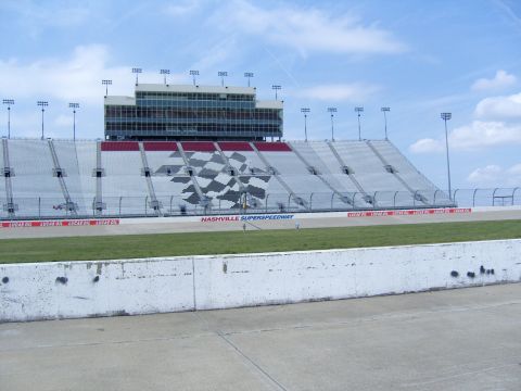 2007 Ford Mustang - The grandstands at Nashville Superspeedway feature a large checkered flag design under a partly cloudy sky.