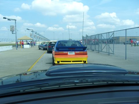2007 Ford Mustang - Cars lined up on a racetrack, with a brightly colored Mustang in the foreground.