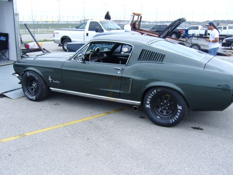 2007 Ford Mustang - A dark green 1967 Ford Mustang Fastback is parked on asphalt next to a trailer and a white pickup truck.