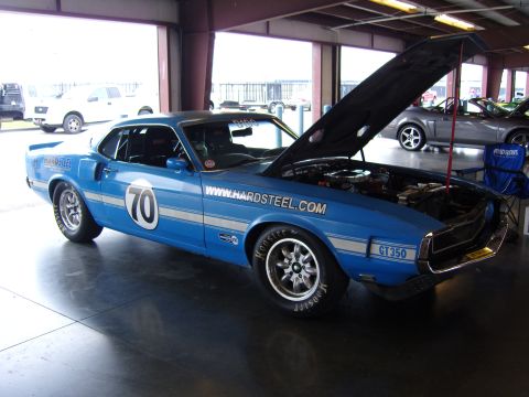 2007 Ford Mustang - A blue 1969 Ford Mustang GT350 race car is parked inside a garage with its hood open, revealing the engine compartment.