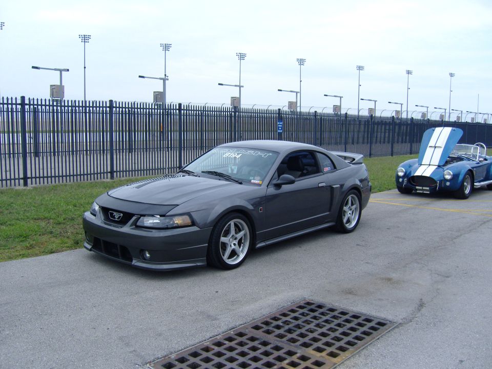 Dark gray 2007 Ford Mustang coupe parked next to a blue convertible with hood up