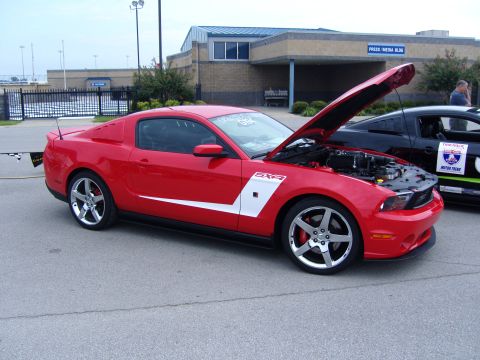 2007 Ford Mustang - A red Ford Mustang is displayed with its hood open, parked next to another vehicle at an outdoor event.