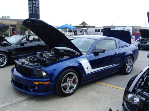 2007 Ford Mustang - A blue 2007 Ford Mustang is displayed with its hood and trunk open at a car show.