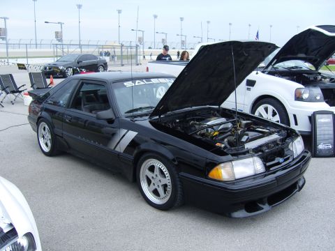 2007 Ford Mustang - A black Saleen Mustang is displayed with its hood open, parked next to a white vehicle at an outdoor car show.