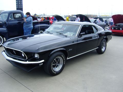2007 Ford Mustang - A black 1969 Ford Mustang is displayed at a car show with other vehicles in the background.