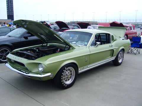 2007 Ford Mustang - A green 1968 Shelby GT350 is displayed with its hood open at a car show, showing off the engine.