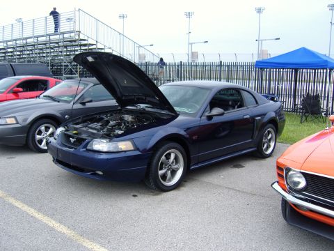 2007 Ford Mustang - Dark blue Ford Mustang GT parked at an outdoor event, hood raised to reveal the engine bay.
