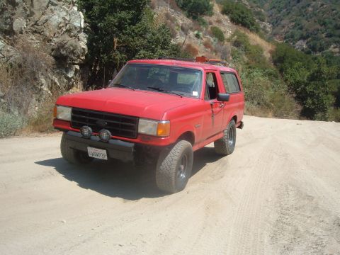 1988 Ford Bronco - This red 1988 Ford Bronco is seen off-road on a dusty trail.
