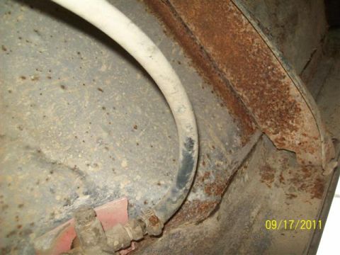 1979 Ford F-150 - Close-up view of a rusted vehicle frame and a fuel line, showing signs of wear and tear.