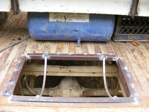 1978 Ford Bronco - The underside of a truck bed is visible, showing the rear axle and suspension system through an opening.