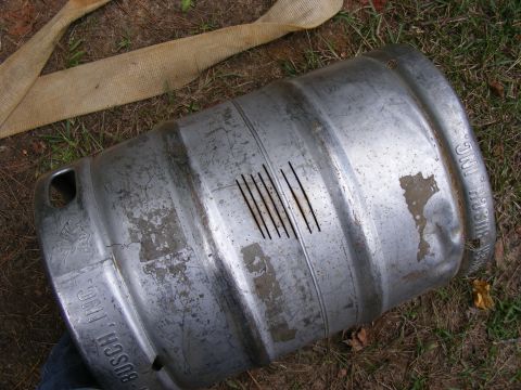 1978 Ford Bronco - A metal keg, possibly for beer, lies on the ground with several scratches visible on its surface.