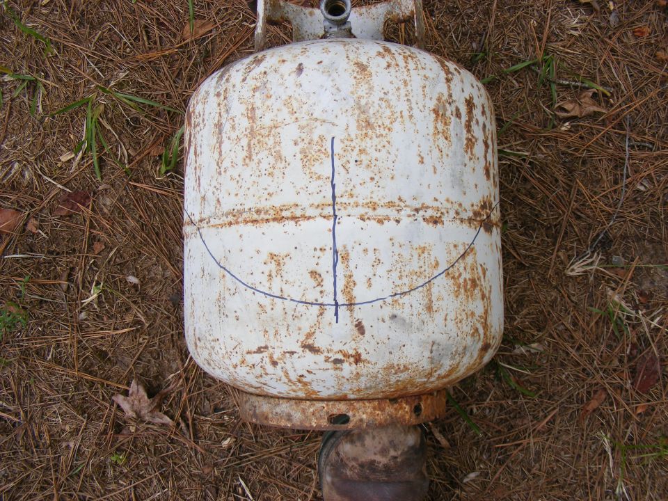 White propane tank with blue markings on the side, resting on the ground
