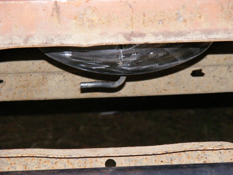 Close-up of a vehicle's underbody fuel tank with a metal strap