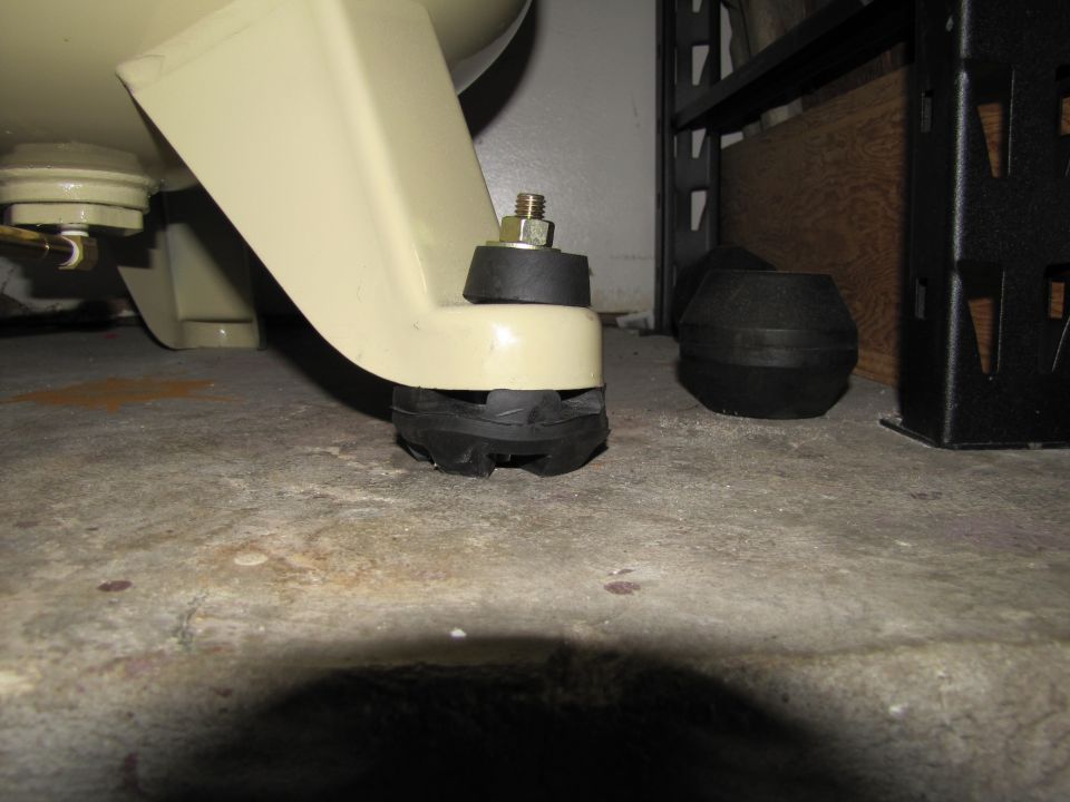 Close-up of rubber and metal mounting feet for an air compressor on a concrete floor