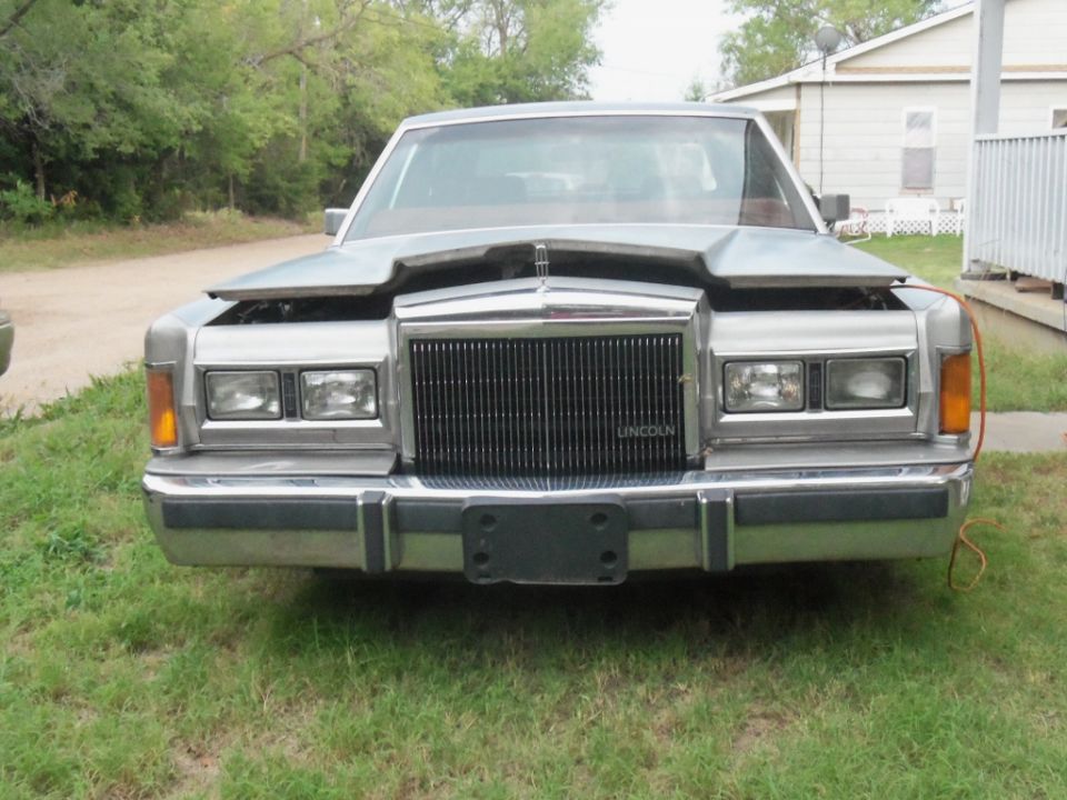 Front view of a silver Lincoln Town Car with hood open and "LINCOLN" text on grille